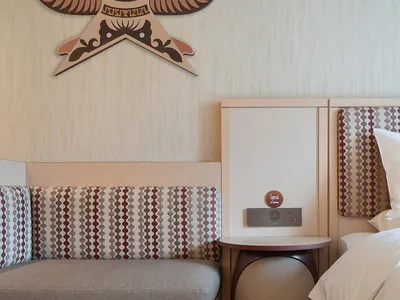 Minimalist hotel room with textured wallpaper, bed, and cushioned seating area.