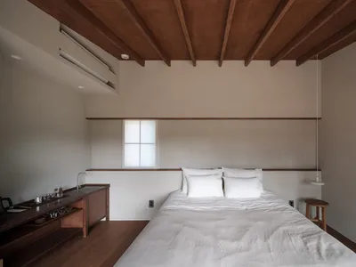 A minimalist bedroom with a bed, white bedding, and a wooden table.