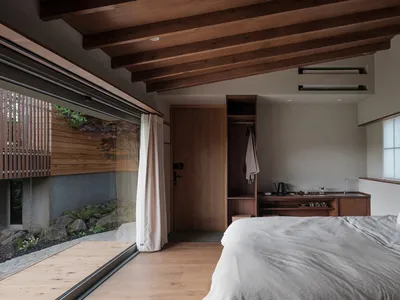 A minimalist bedroom with okiriko wood flooring and a view of a garden.