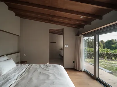 A minimalist bedroom with wooden walls and a bed with a wooden headboard.