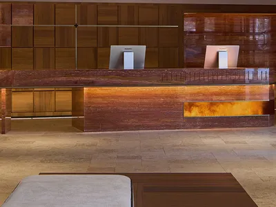 A modern hotel lobby with a wooden reception desk and marble accents.