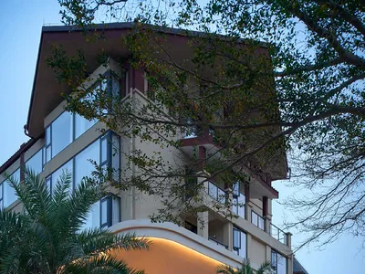 Modern hotel exterior featuring concrete, glass, and palm trees.