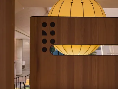 A modern restaurant bar with a wooden counter featuring integrated circular yellow lights.
