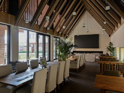 Industrial restaurant interior featuring concrete walls, wooden tables, and glass windows.