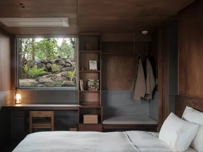 A minimalist bedroom featuring a wooden kitchenette with a view of the outdoors.