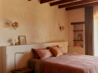 Minimalist bedroom featuring fabric bedding and wooden beams on the ceiling.