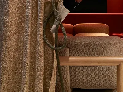 A textured fabric curtain with a rope tieback in a cozy residential living room setting.