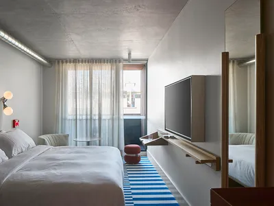 A minimalist bedroom with concrete surfaces and fabric furnishings.