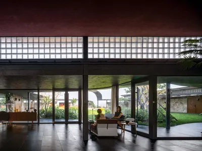 Interior design of a minimalist hotel lobby with concrete walls and floors, glass block windows, and large windows looking ou