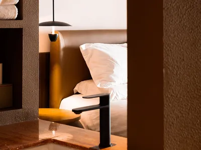 A modern, minimalist bedroom with textured concrete walls and a sleek, white bed.