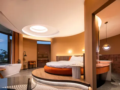 Modern minimalist bedroom with circular bed, large window, and circular ceiling light.