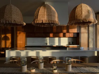 A modern kitchen featuring natural fiber lighting fixtures and wooden stools.