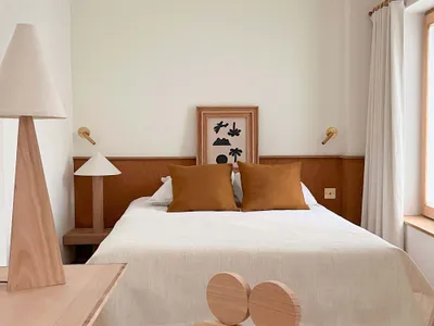 A minimalist bedroom with wooden furniture and a white bed.