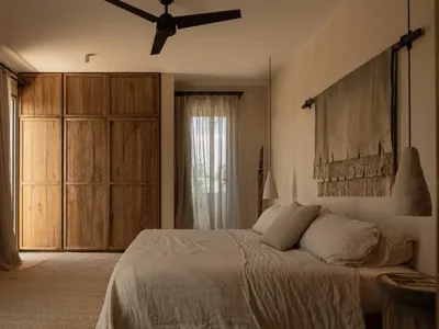 A minimalist bedroom features wooden cabinets and neutral textiles, creating a serene and functional space.