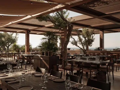Modern restaurant interior with industrial design features, including wooden tables and glass elements.