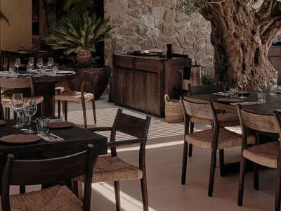 A modern restaurant interior featuring wooden furniture and stone walls.