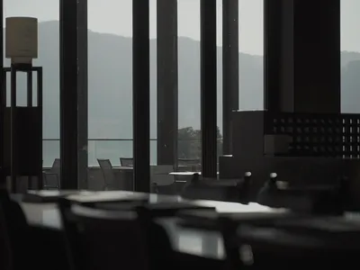 Empty modern restaurant with black glass and concrete bar, featuring sleek design and minimalist aesthetic.