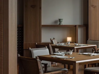 A modern restaurant interior featuring wooden tables and chairs, with a minimalist decor and soft lighting.