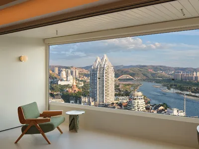 View from a window overlooking a modern hotel complex with a river and cityscape in the background.