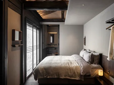 A minimalist bedroom featuring a wooden bed and clean, simple decor.