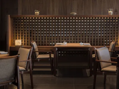 Modern restaurant interior with wooden furniture and lattice partitioning.