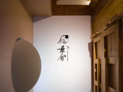 簡約木質室內空間，搭配白色圓形燈具與牆面傳統日式書法。