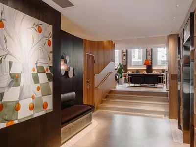 A hotel lobby with wooden benches, tiled floors, and modern furniture.