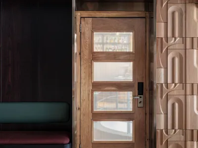 Modern wooden restaurant entrance with glass panels and bench seating.