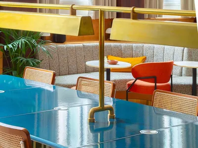 A modern restaurant interior featuring metallic tiles, wooden chairs, and a vibrant seating area.