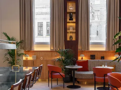 A modern restaurant interior featuring wooden flooring, leather seating, and metal accents.