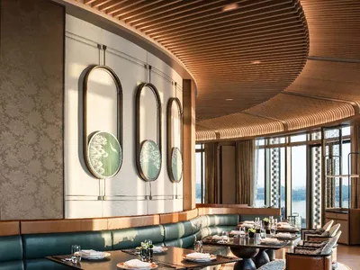 Luxurious restaurant interior with wooden slat ceiling, green banquettes, and wooden tables.