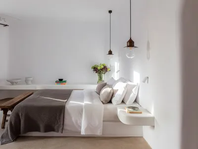 Modern minimalist bedroom featuring a concrete floating bed, white bedding, and minimalist decor.
