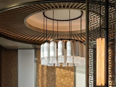 Modern restaurant interior with marble tables, glass chandelier, and fabric chairs