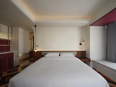 A modern bedroom featuring white walls, concrete flooring, wooden accents, and a minimalist design.