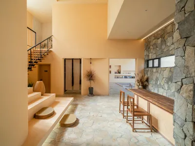 A modern hotel lobby with a neutral color scheme featuring a stone fireplace and wooden furniture.