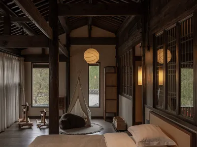 A minimalist bedroom featuring natural wood materials and a teepee tent for relaxation.
