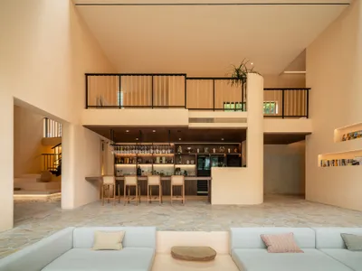 A modern minimalist living room with concrete walls and wooden accents, featuring a comfortable seating area and a bar counte