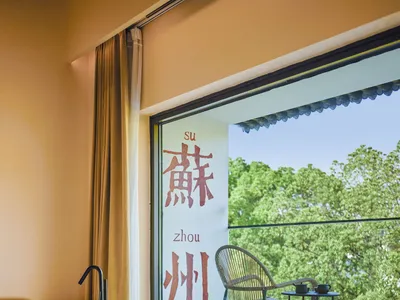A modern hotel room featuring a glass window overlooking green trees.