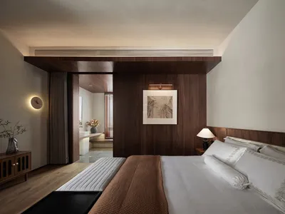 Modern minimalist bedroom with white bedding and wood accents.