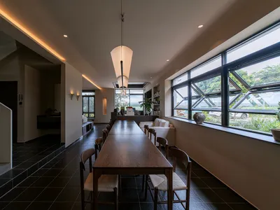 現代餐廳室內，木質餐桌、玻璃窗與混凝土地板。