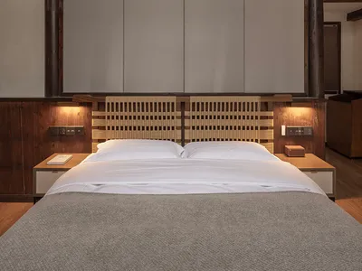 Modern minimalist bedroom featuring a wooden frame and woven headboard with white furniture, designed for relaxation and simp