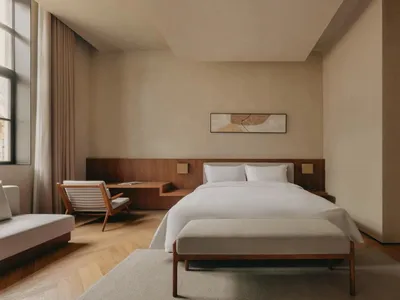 Modern minimalist bedroom with wooden furniture, white bedding, and a large window