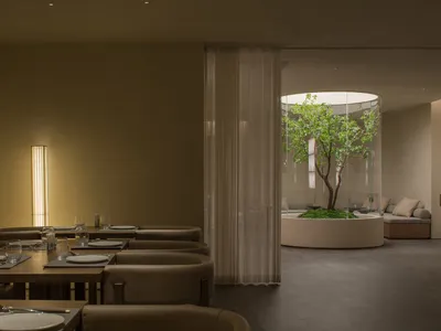 A modern restaurant interior featuring glass walls, marble tables, and contemporary lighting.