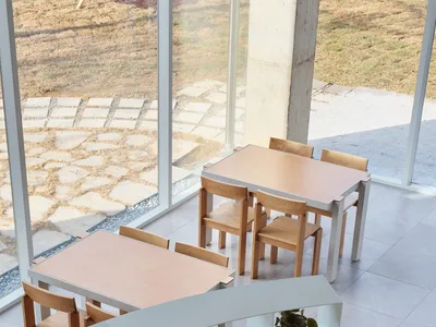 A modern restaurant interior featuring tables, chairs, and plants.