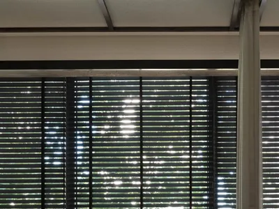 A minimalist bedroom with window blinds and a curtain.