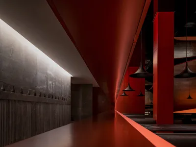 A sleek, modern food court with red metallic walls and pendant lights hanging from the ceiling.