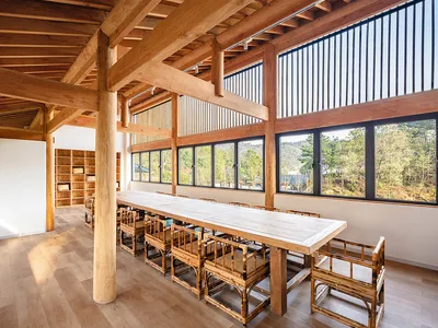 Modern restaurant interior with wooden ceiling and tables.
