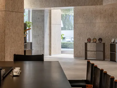 An industrial-style restaurant interior with concrete walls, minimalist decor, and modern seating.