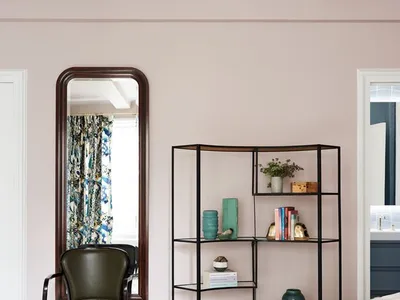 A modern minimalist bedroom with light-colored walls, metal shelving, and fabric curtains.
