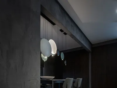 深色混凝土餐廳搭配現代燈具與木地板。